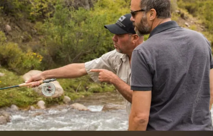 Dos pescadores junto a un arroyo de montaña, uno con la caña en la mano
